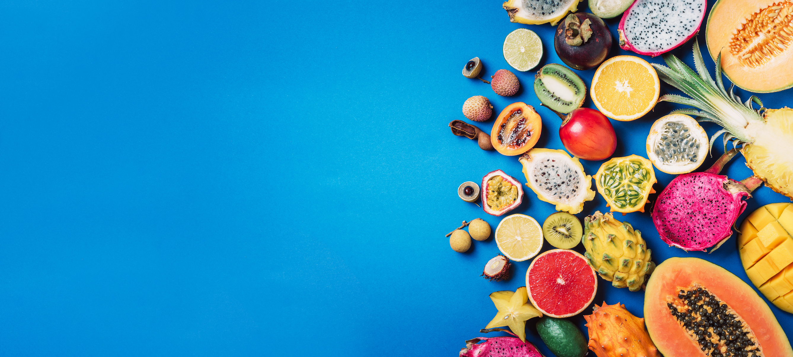 Exotic Fruits - Pineapple, Papaya, Mango, Annona, Banana, Pitahaya, Kiwano, African Horned Melon, Tamarillo Fruit, Granadilla, Salak, Snake Fruit, Maracuya, Rambutan, Lychee, Longan, Tamarind, Mangosteen on Blue Background. Tropical Fruits Concept. Top Vi
